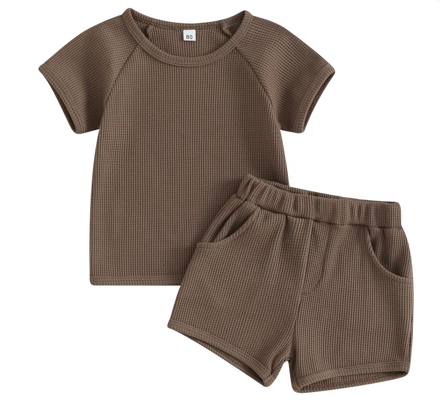 A unisex baby and toddler waffle-knit loungewear set in a rich coffee brown colour, including a short-sleeved top and matching shorts with pockets.