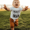 A baby and toddler boy's two-piece set, featuring a white cotton t-shirt with "Mama's Little Man" in black print and a pair of rich tan shorts with a drawstring.