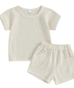 A unisex baby and toddler waffle-knit loungewear set in a soft, natural cream colour, including a short-sleeved top and matching shorts with pockets.