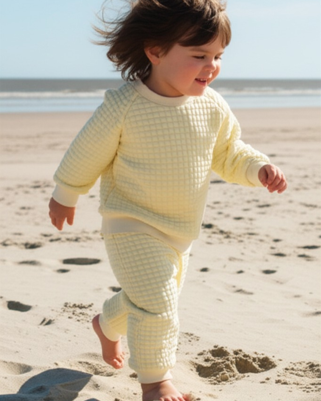 A unisex children's loungewear set in a soft, buttermilk yellow quilted fabric, including a long-sleeved top and matching jogger trousers.
