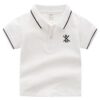 A smart boy's polo shirt in crisp white, featuring a collar and cuffs with classic navy blue tipping stripes, and a small embroidered crest on the chest.